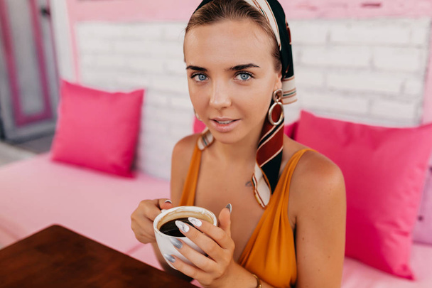 Zbliżenie na zewnątrz portret eleganckiej stylowej kobiety z niebieskimi oczami i pięknym uśmiechem do picia kawy i patrząc na kamerę  - Zdjęcie, obraz