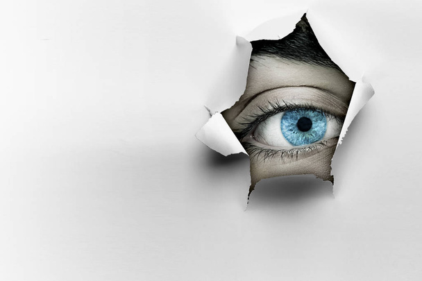 Eye in a hole of torn paper - Foto, afbeelding
