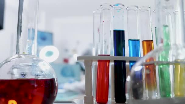 POV shot των σωλήνων με διάφορα χρωματιστά υγρά πλησιάζει έναν ερευνητή στο εργαστήριο - Πλάνα, βίντεο