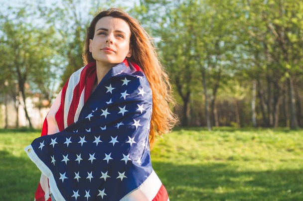 アメリカ国旗を持つ幸せな女性は7月4日を祝う - 写真・画像