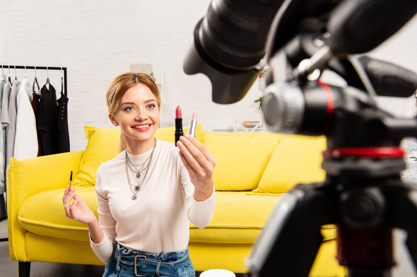 smiling beauty blogger holding lipsticks in front of video camera - Fotoğraf, Görsel