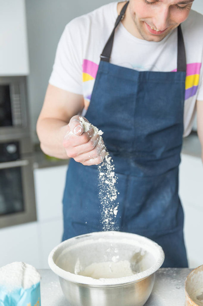 hands sifting flour by sieve in iron bowl - Foto, imagen