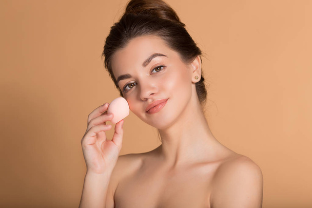 Closeup portrait of young beautiful woman is holding beauty blender for applying makeup foundation . Skin care and beauty concept. - Fotografie, Obrázek