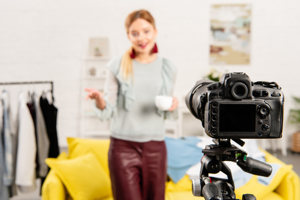selective focus of blogger holding cup of coffee in front of video camera - Zdjęcie, obraz