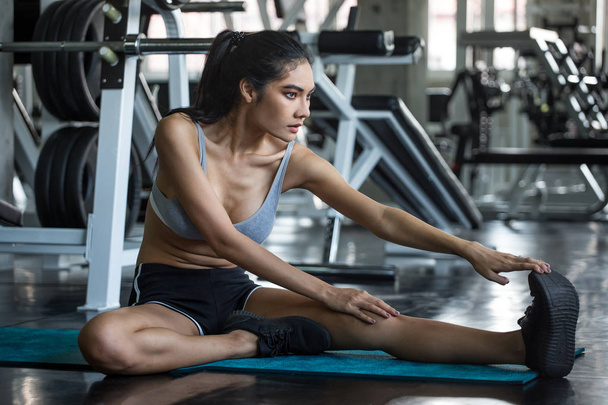 jeune femme de fitness étirant sa jambe pour se réchauffer assis sur le tapis
 - Photo, image