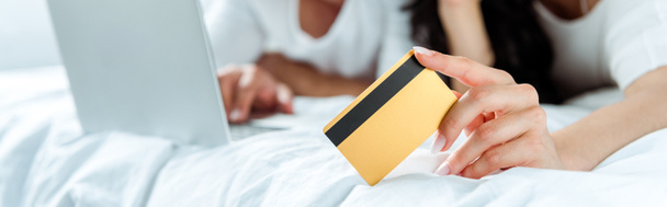 foyer sélectif de la femme tenant la carte de crédit près de l'homme avec ordinateur portable, tir panoramique
 - Photo, image