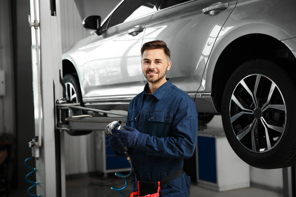 Technician with tool in automobile repair shop - Fotoğraf, Görsel