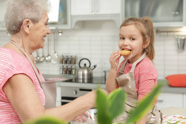 Cute girl and her grandmother cooking in kitchen - Foto, Bild