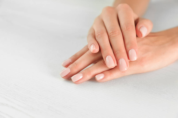Closeup view of woman with smooth hands and manicure at table, space for text. Spa treatment - Photo, image