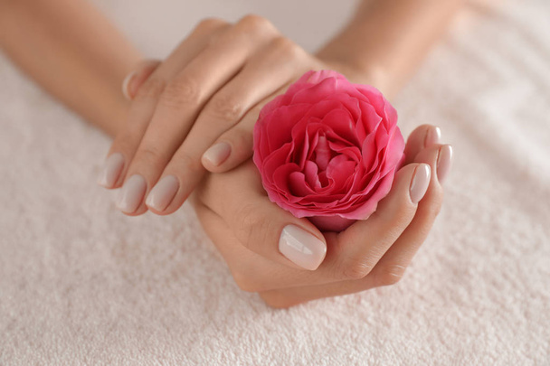 Woman with smooth hands and flower on towel, closeup. Spa treatment - Foto, Imagen