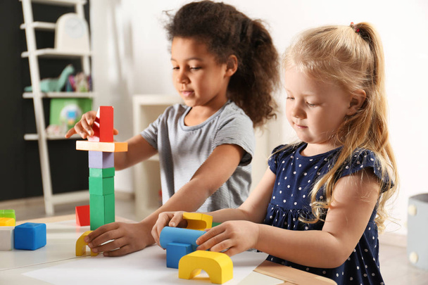 Cute little children playing with building blocks in kindergarten. Indoor activity - Fotó, kép