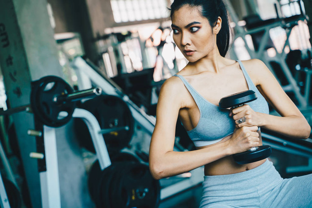 Wellbeing smart asian sport women lifting dumbbell in gym - Photo, Image