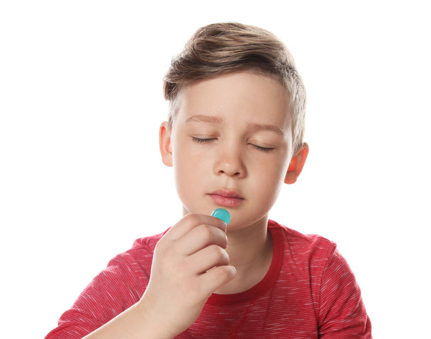 Little child taking pill on white background. Danger of medicament intoxication - Foto, Imagen