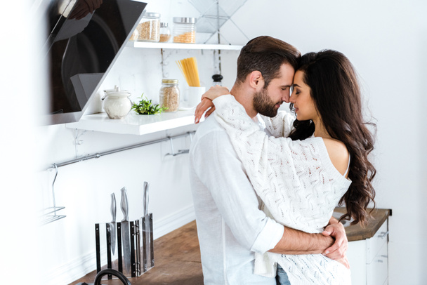 beau couple embrassant doucement avec les yeux fermés à la cuisine
 - Photo, image