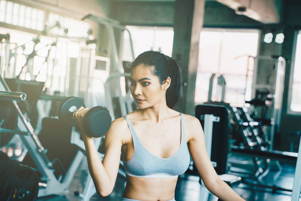 Bienestar inteligente asiático deporte mujeres lifting dumbbell en gimnasio
 - Foto, imagen