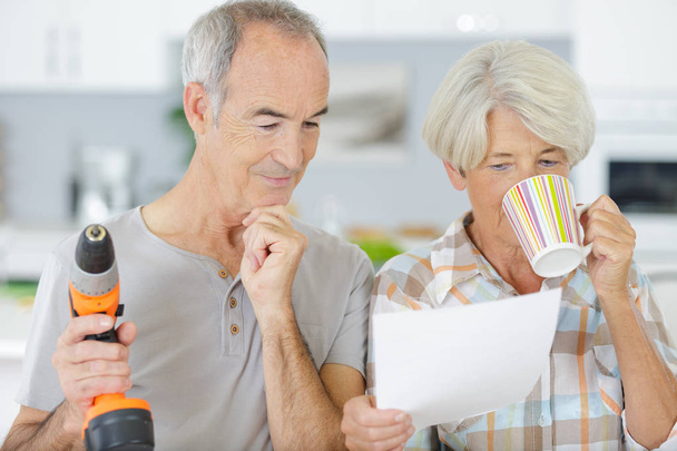 senior couple looking at plan of new kitchen - 写真・画像