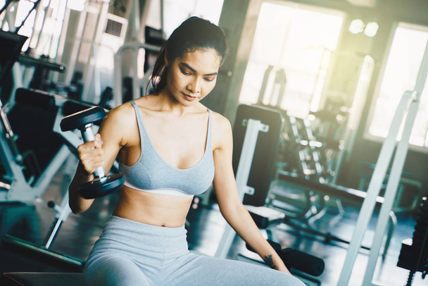 Wellbeing smart asian sport women lifting dumbbell in gym - Photo, image