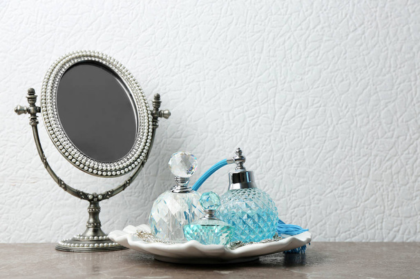 Plate with perfume bottles and jewellery near mirror on dressing table. Space for text - Фото, изображение