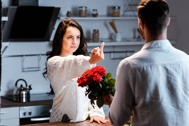 zły kobieta pokazując środkowy palec do człowieka z bukiet róż  - Zdjęcie, obraz