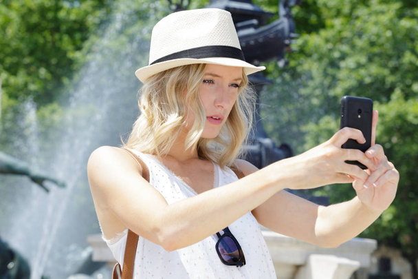 woman taking selfie in front of fountain - Фото, зображення