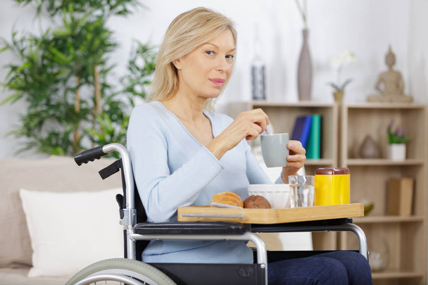 happy handicapped senior woman having a cup of coffee - 写真・画像