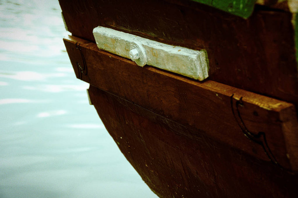 Старая деревянная лодка корма на реке и фонтан позади
 - Фото, изображение