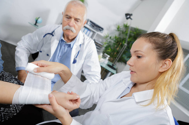 Krankenschwester bandagiert Patienten am Handgelenk - Foto, Bild