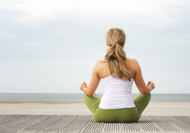 Retrato retrovisor de una joven sentada en la playa en pose de yoga
 - Foto, Imagen
