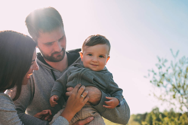 Happy family with cute baby boy on sky background outdoors, sensitivity to nature concept - Foto, afbeelding