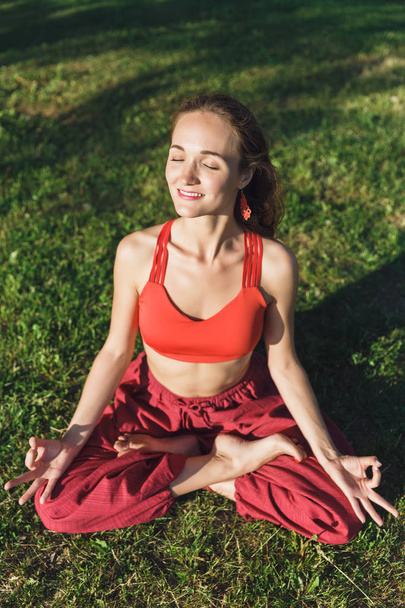 ヨガを屋外で練習している若い女性。夏の都市公園の女性瞑想屋外. - 写真・画像