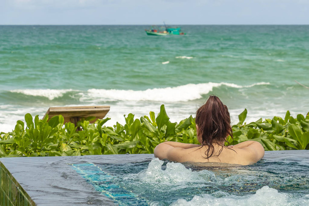 Feminino em um resort de praia piscina olhando para o mar aberto
 - Foto, Imagem