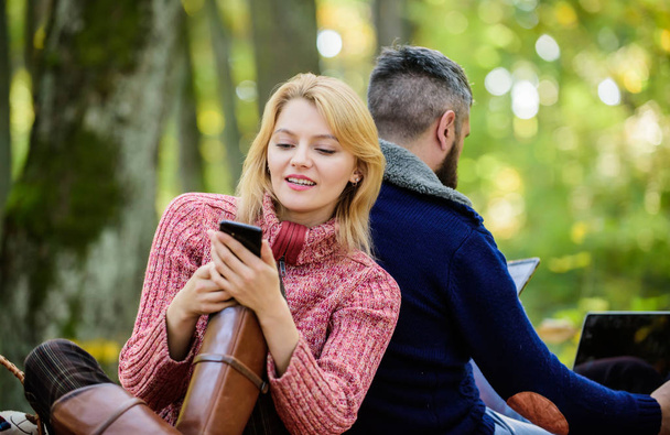 Modern people always involved online communication. Online life modern technology. Logout of all accounts. Modern life. Happy loving couple relaxing in park with mobile gadgets. Internet addiction - Фото, изображение