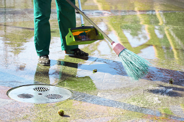 zelador limpa a calçada da cidade de folhas caídas
 - Foto, Imagem