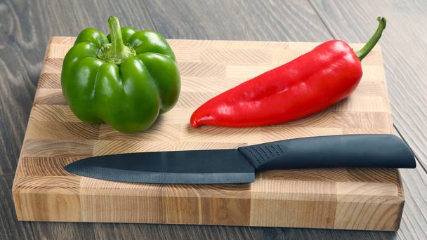 sweet peppers with a ceramic knife on a wooden board - Photo, Image