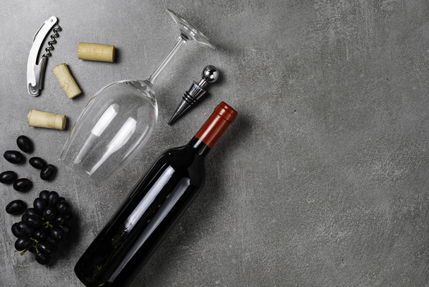 Wine bottle, glass, opener and grapes on concrete background. Copy Space. - Photo, Image