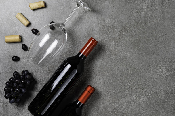 Bottiglie di vino, coppa, tappi di sughero e uva su sfondo concreto. Copia spazio
 - Foto, immagini