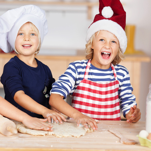 Girl Using Cookie Cutters On Dough With Sisters At Kitchen Count - Foto, imagen