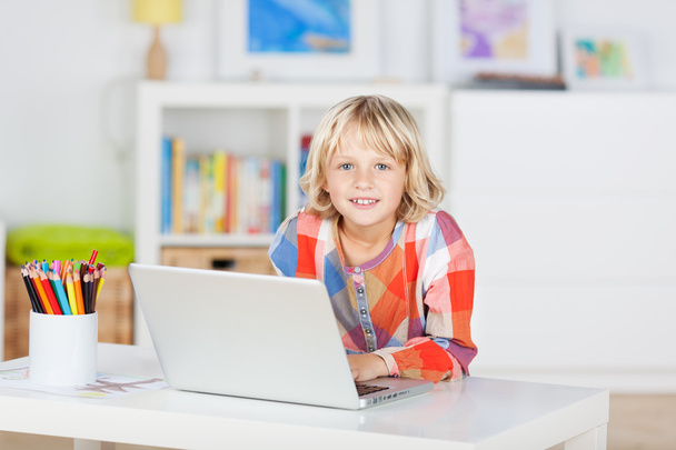Small young girl smiling and using a laptop - Foto, Imagen