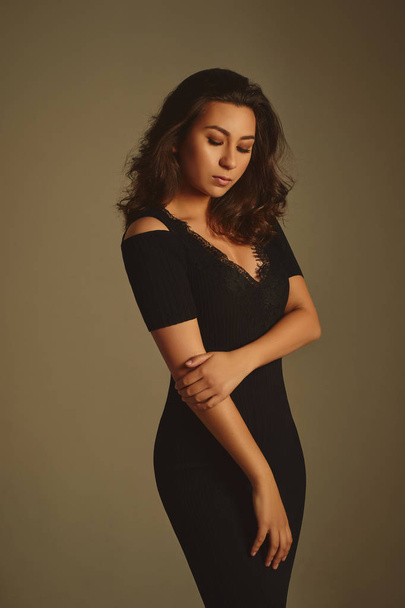 Sensual brunette woman in black dress posing in studio  - Fotó, kép
