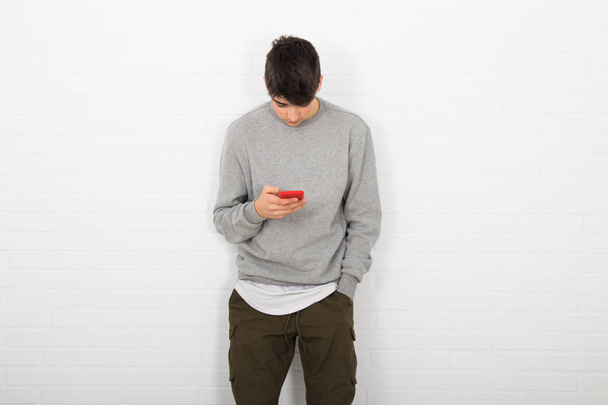 νεαρός άνδρας στον τοίχο με κινητό τηλέφωνο - Φωτογραφία, εικόνα