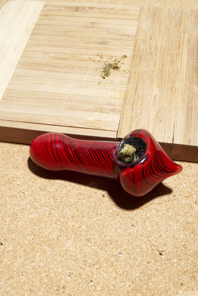 Ahşap masa üzerinde marihuana ve kırmızı sigara borusu - Fotoğraf, Görsel