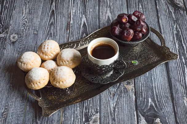 Vista superior en plato de plata con dulces, frutas dátiles y taza de café en la mesa de madera oscura. Fondo del Ramadán
 - Foto, Imagen