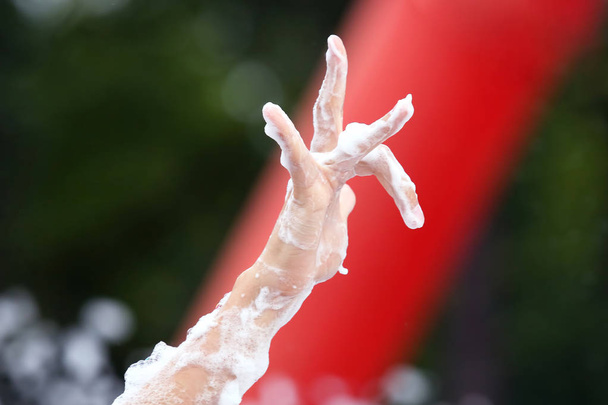 de hand van een man in een zeep schuim op het concert - Foto, afbeelding