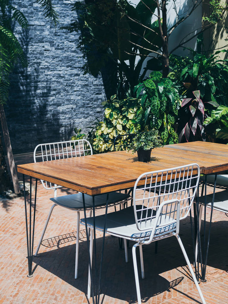 Tavolo da pranzo in legno con sedie bianche nel giardino esterno
 - Foto, immagini