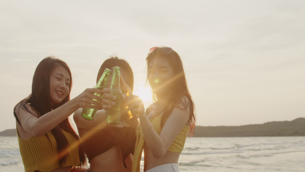 Група азіатських дівчаток-підлітків, що мають учасник святкування на пляжі, друзі щасливі пити пиво на пляжі в море, коли захід сонця у вечірній час. Відкритий подорожі відпустку відпустку Літня концепція. Повільний рух постріл. - Кадри, відео