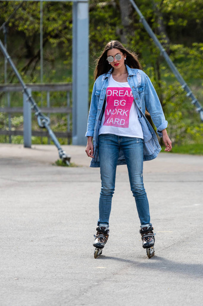 DOBELE, LATVIA, - MAY 7, 2019:  A young woman in sunglasses on roller skates. - Фото, зображення