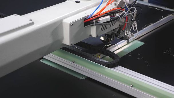 La robótica trabaja en la línea de producción de sastrería. El ordenador controla la máquina de coser. patrón de bordado de aguja en cuero artificial. Robot máquina de coser. máquina de coser automática
. - Foto, Imagen