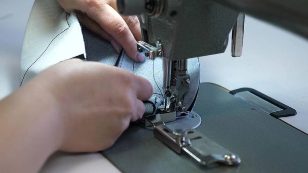 革製品を縫うプロセス。動いているミシンの針。ミシンの2本の針は、すぐに上下に移動し、クローズアップ。テーラーは縫製ワークショップで黒い革を縫う. - 写真・画像
