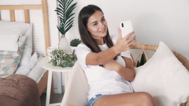 Beautiful girl takes selfie or video on phone, sends air kiss, slow motion - Felvétel, videó