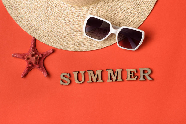 Z dřevěných dopisů slovo léto. Sluneční brýle, část klobouku a hvězdičky. Živá korálová pozadí. Koncepce cestování - Fotografie, Obrázek